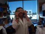Team member holding two round glass trays as if they were eyeglasses