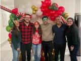 Six lab team members posed in front of a red, white, green, and gold balloon arch, 3 wearing Halloween masks.