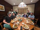 Nine people pose for the camera around a table in a restaurant