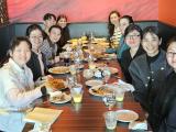 10 men and women seated in a restaurant booth, with plates of food.