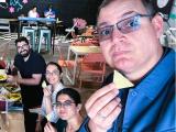 four people seated at a table, each holding a tortilla chip