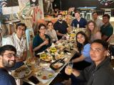 a group of people seated around a table enjoying tacos and beer