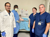 Four people wearing medical attire, standing in a lab.