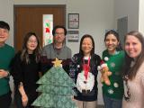 members of the Dan Tong lab gathered in front of a doorway with Christmas sweaters and a paper Christmas tree