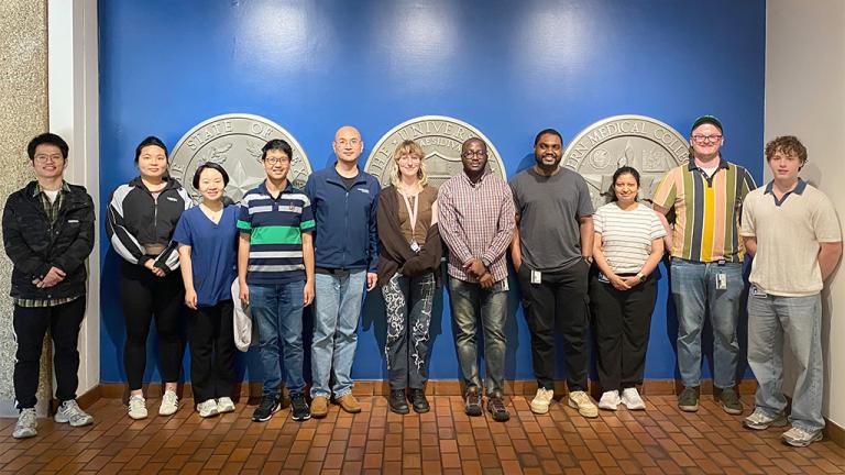 stone chen lab members standing infront of the UT Southwester Seal wall