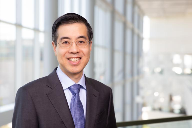 Dr. Thomas J. Wang wearing a dark colored suit standing in a hospital lobby