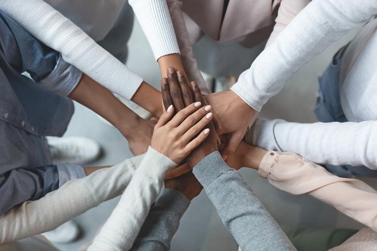 Diverse circle of people with hands in the middle