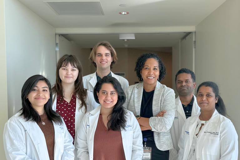 The Harris-Tryon lab group posing wearing white lab coats.