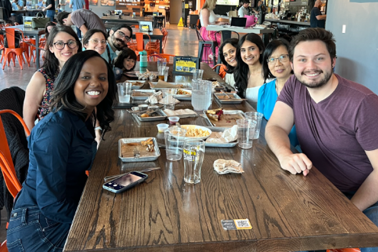 Group photo with Dr. Josephine Thinwa and the other lab members around a table at a restaurant.