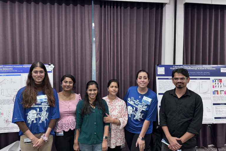 A group of six people standing in front of presentation posters.