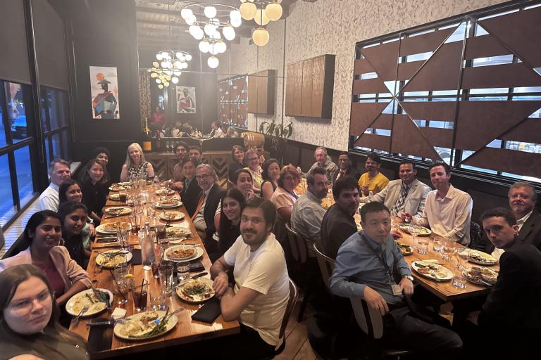 A large group of people sitting at two different tables at a restaurant.