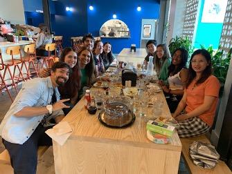 Ten lab members at a restaurant table, with a large cake.