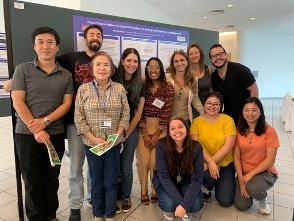 Eleven lab team members stand in front of a poster presentation.