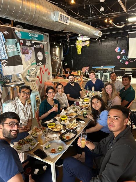 a group of people seated around a table enjoying tacos and beer