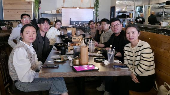 Lab team members pose around table while enjoying lunch together. 