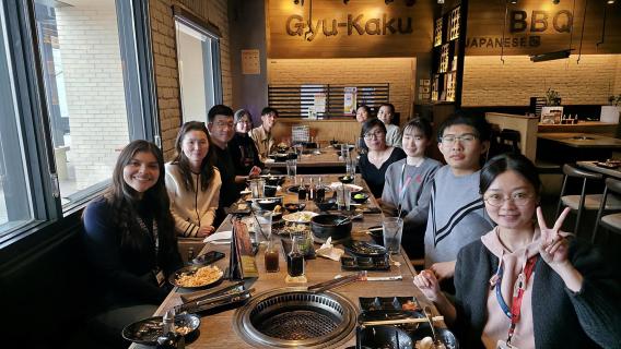 Lab team members pose while gathered around dining table enjoying lunch together 