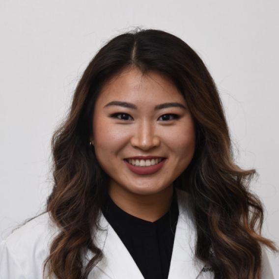 Smiling woman with long dark hair, wearing a lab coat.