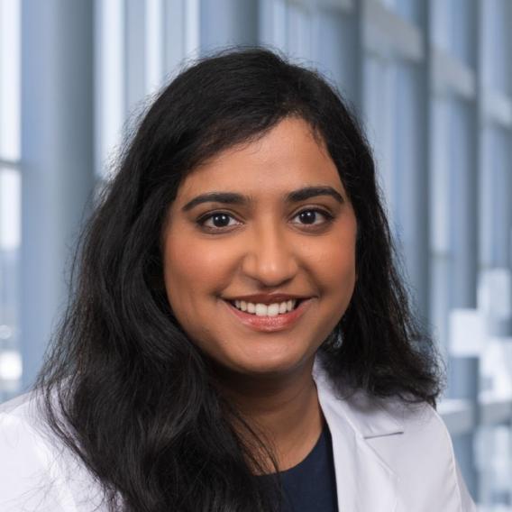 a woman with long dark hair wearing a white lab coat