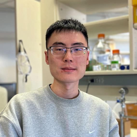 Lirong Zheng wearing a grey sweatshirt standing in a laboratory setting