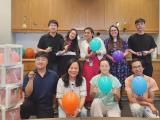 Dr. Dan Tong with eight lab members holding balloons in the lab