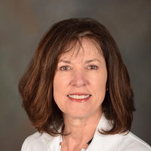 Dr. Wise, smiling woman with dark hair, wearing a lab coat embroidered with "Carol Wise, M.D. - Research Dept."