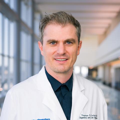 Dr. Thomas Cotter wearing a white coat standing in a hospital lobby