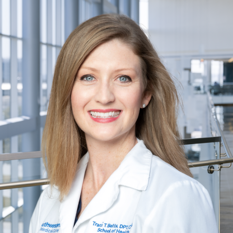 a woman with blonde hair wearing a white lab coat standing in a hospital lobby