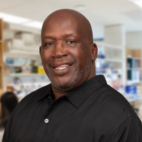 Eston Dixon dressed in a black shirt standing in a laboratory