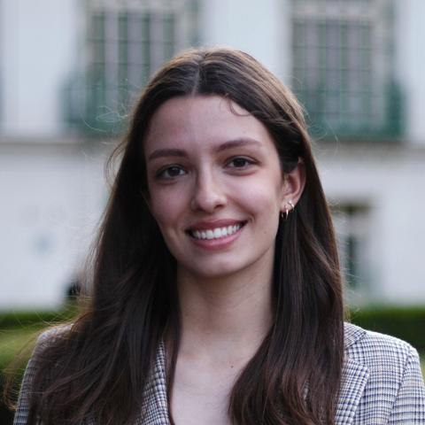 a woman with long brown hair standing in front of a building