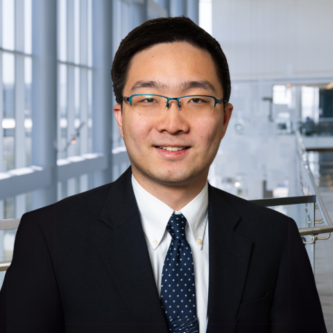 Bill Zhang wearing a dark suit and patterned necktie in the lobby of Clements University Hospital