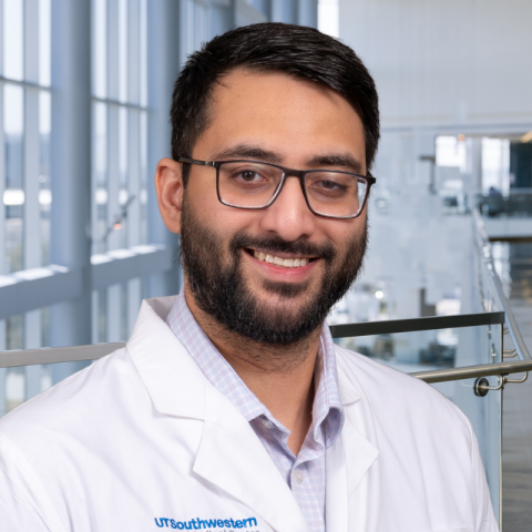 a man with short dark hair wearing glasses and a white lab coat