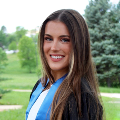 Lauren Kemp a woman with long hair staning in front of a group of trees